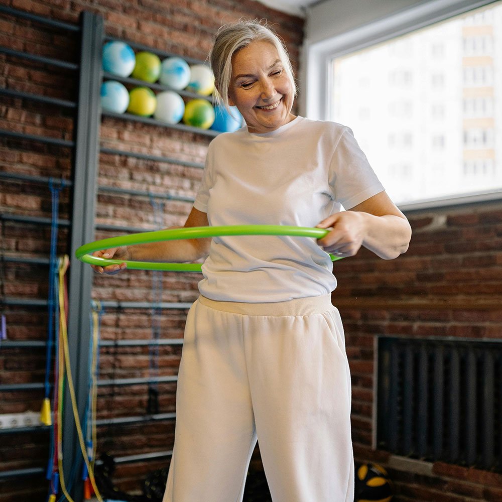 Elderly woman exercising with hula hoop